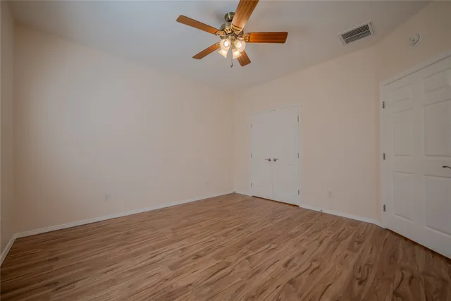 a view of a room with wooden floor and a ceiling fan