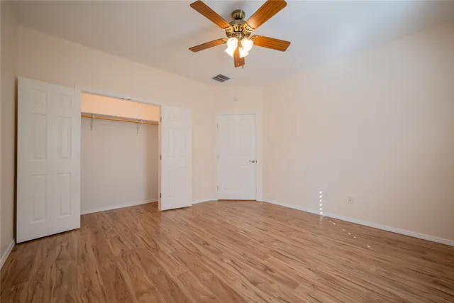 a view of a room with wooden floor and a ceiling fan