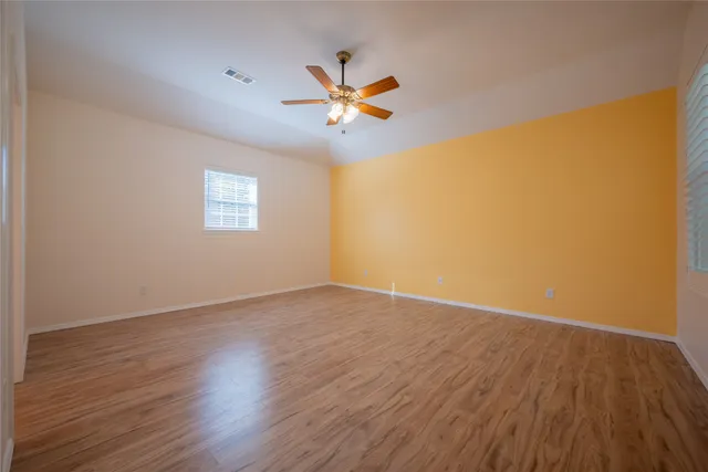 a view of empty room with wooden floor and fan