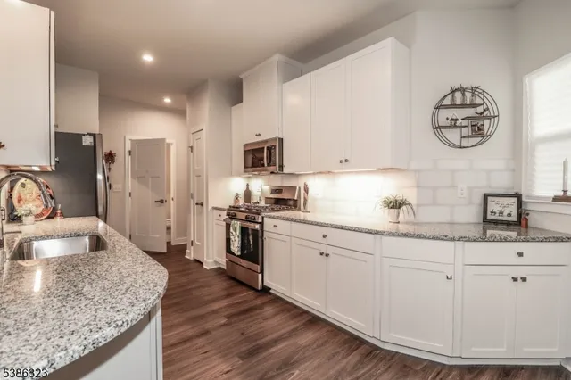 a kitchen with granite countertop a sink stove and refrigerator