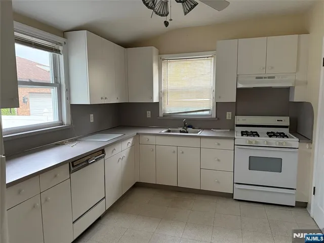 a kitchen with cabinets appliances a sink and a window