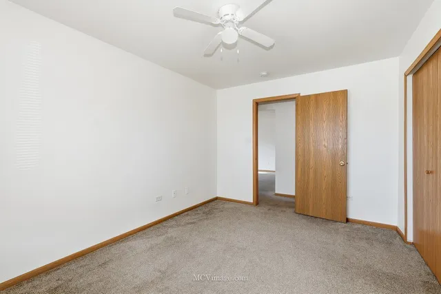 an empty room with a ceiling fan and carpet