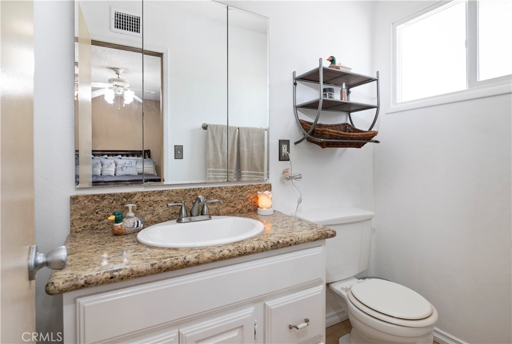 10409 Pendleton Street Riverside, CA 92505 - Photo 22 of 35 a bathroom with a granite countertop sink a toilet and a mirror