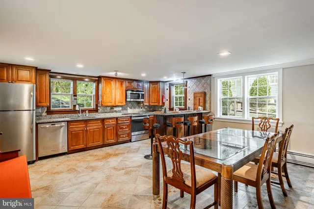 a kitchen with stainless steel appliances granite countertop a stove a sink a refrigerator dining table and chairs