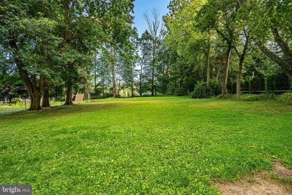 a view of house in front of a big yard with large trees
