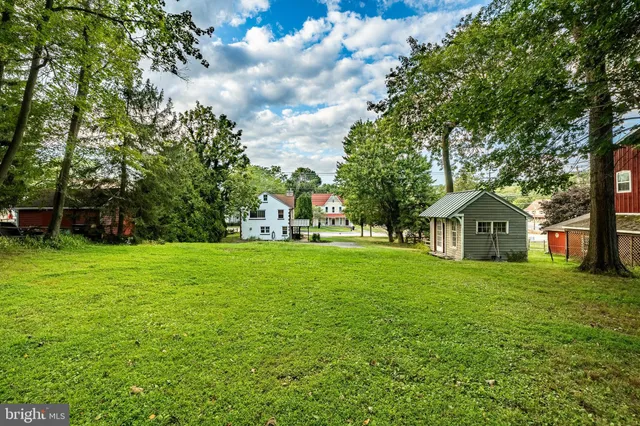 a view of a white house with a big yard and large trees