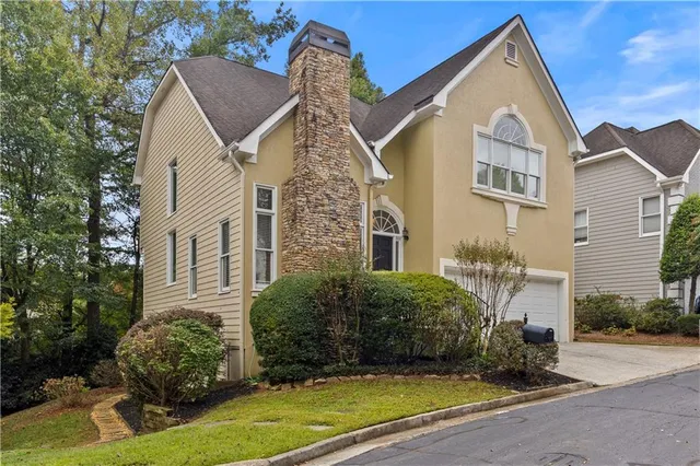 a view of a white house next to a yard with potted plants