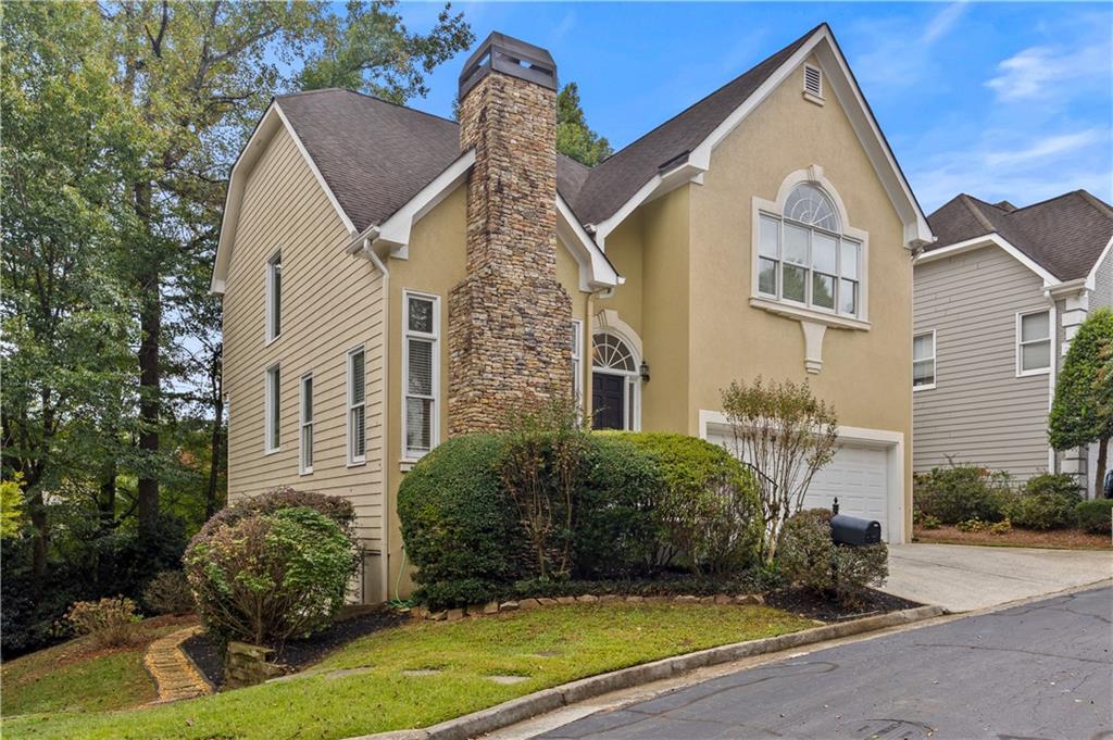 a view of a white house next to a yard with potted plants