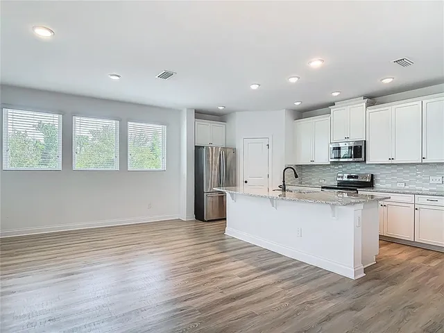 a kitchen with stainless steel appliances granite countertop a stove top oven a sink and a refrigerator