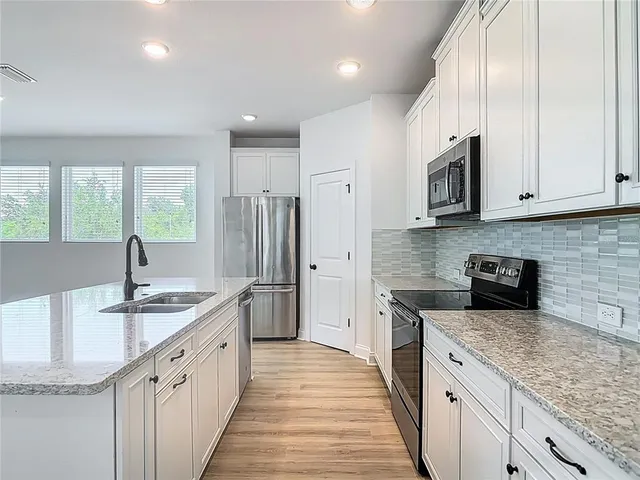 a kitchen with stainless steel appliances granite countertop a sink stove and refrigerator