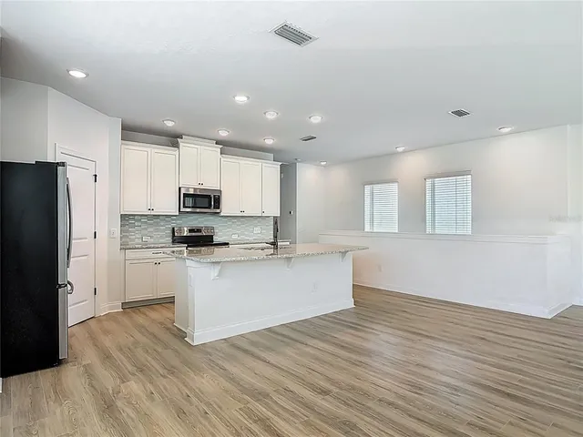 a kitchen with a refrigerator and white cabinets