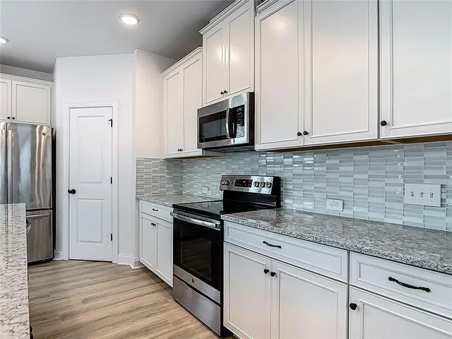 a kitchen with stainless steel appliances granite countertop a stove a refrigerator and a microwave