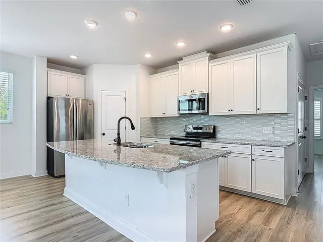a kitchen with stainless steel appliances granite countertop a stove top oven a sink and dishwasher with wooden floor