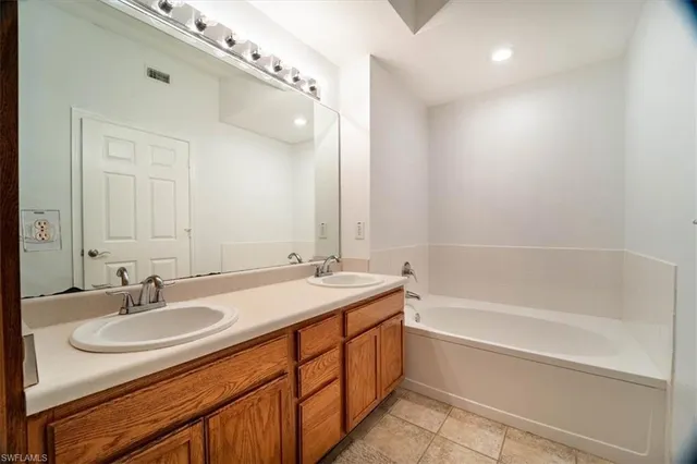 a bathroom with a granite countertop sink a mirror a vanity and bathtub