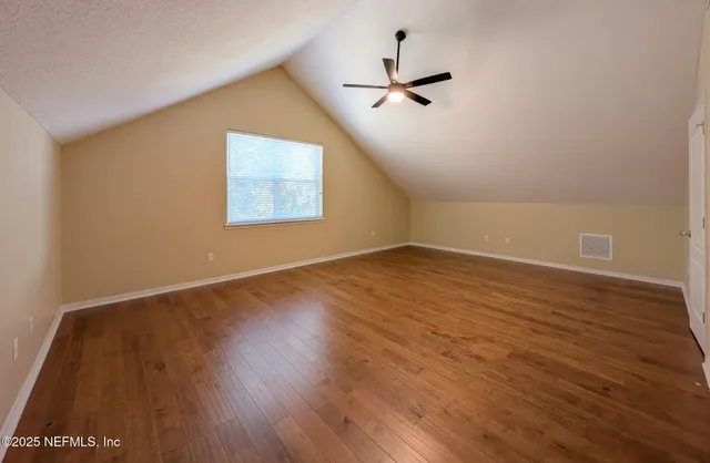 a view of empty room with wooden floor and fan