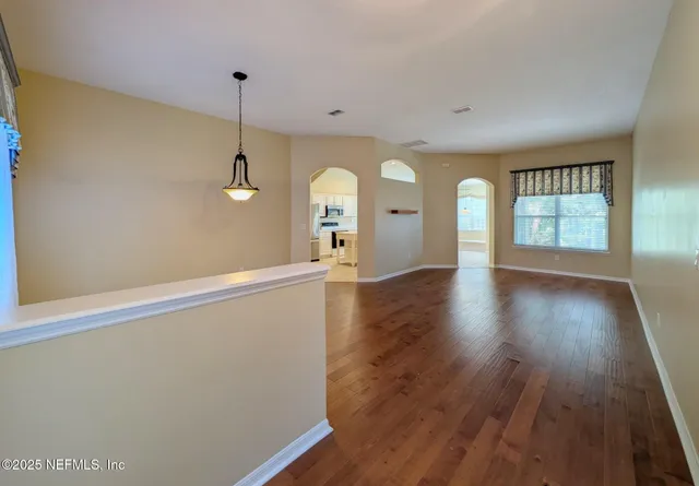 a view of an empty room with window and wooden floor