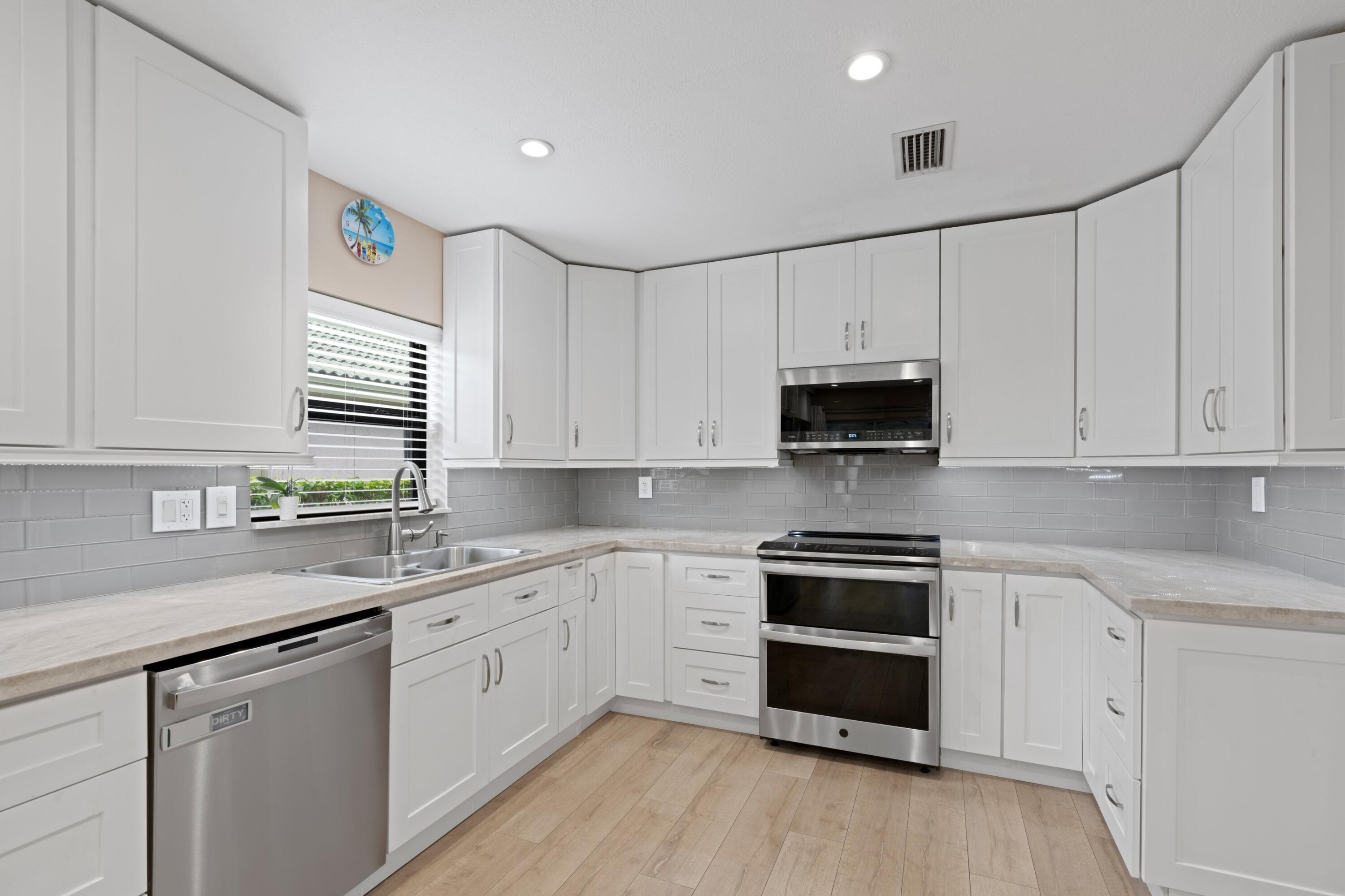 7980 Cloverfield Circle Boca Raton, FL 33433 - Photo 6 of 44 a kitchen with granite countertop white cabinets and white appliances