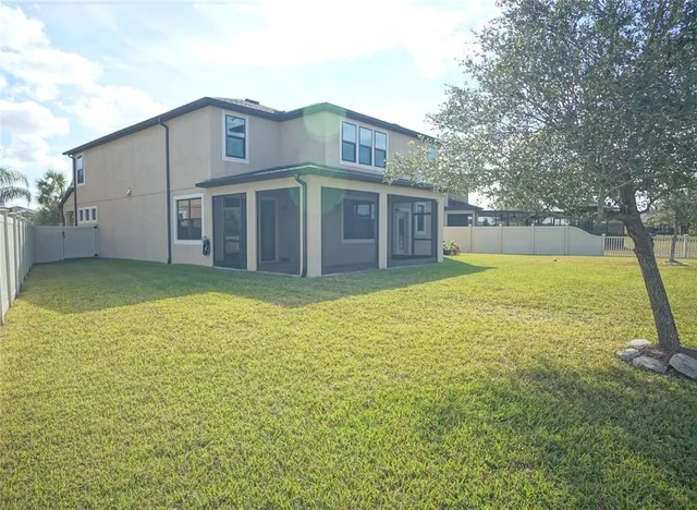 a view of a house with a yard and a large tree