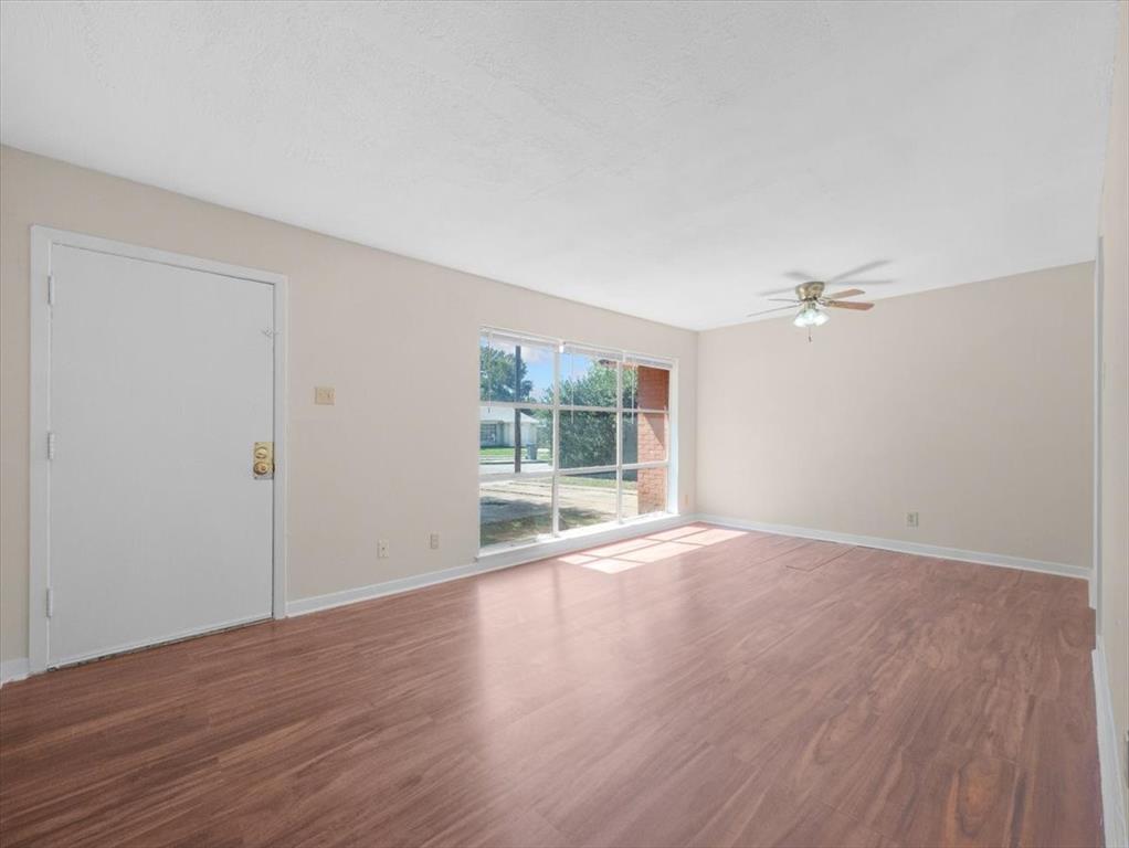 403 Rolando Drive Garland, TX 75040 - Photo 5 of 25 a view of an empty room with wooden floor and a window