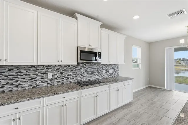 a kitchen with granite countertop white cabinets and stainless steel appliances