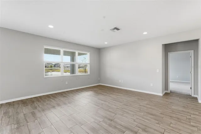 an empty room with wooden floor and windows