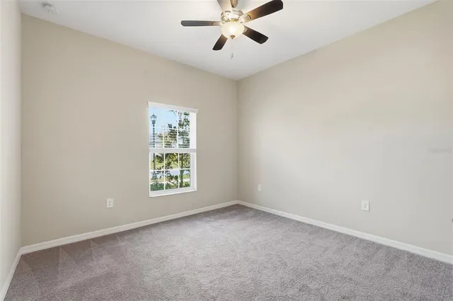 an empty room with windows and ceiling fan