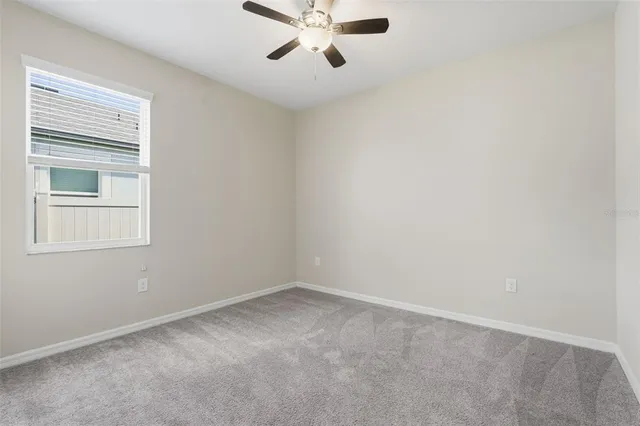 an empty room with a window and a fan