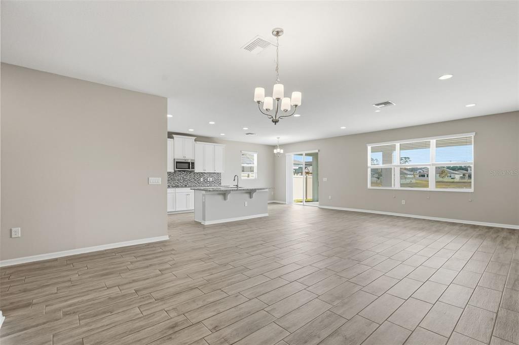 17618 Cortes Creek Boulevard Spring Hill, FL 34610 - Photo 9 of 40 a view of an empty room with wooden floor and kitchen view
