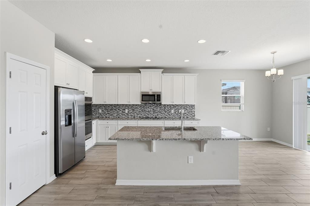 17618 Cortes Creek Boulevard Spring Hill, FL 34610 - Photo 10 of 40 a large kitchen with stainless steel appliances granite countertop a stove a refrigerator a sink and white cabinets with wooden floor