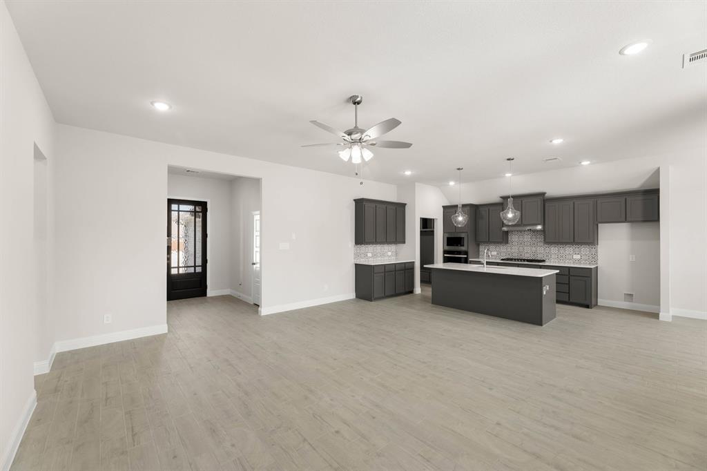1007 Sedona Trail Justin, TX 76247 - Photo 5 of 40 a large kitchen with stainless steel appliances a large counter top a stove and a chandelier