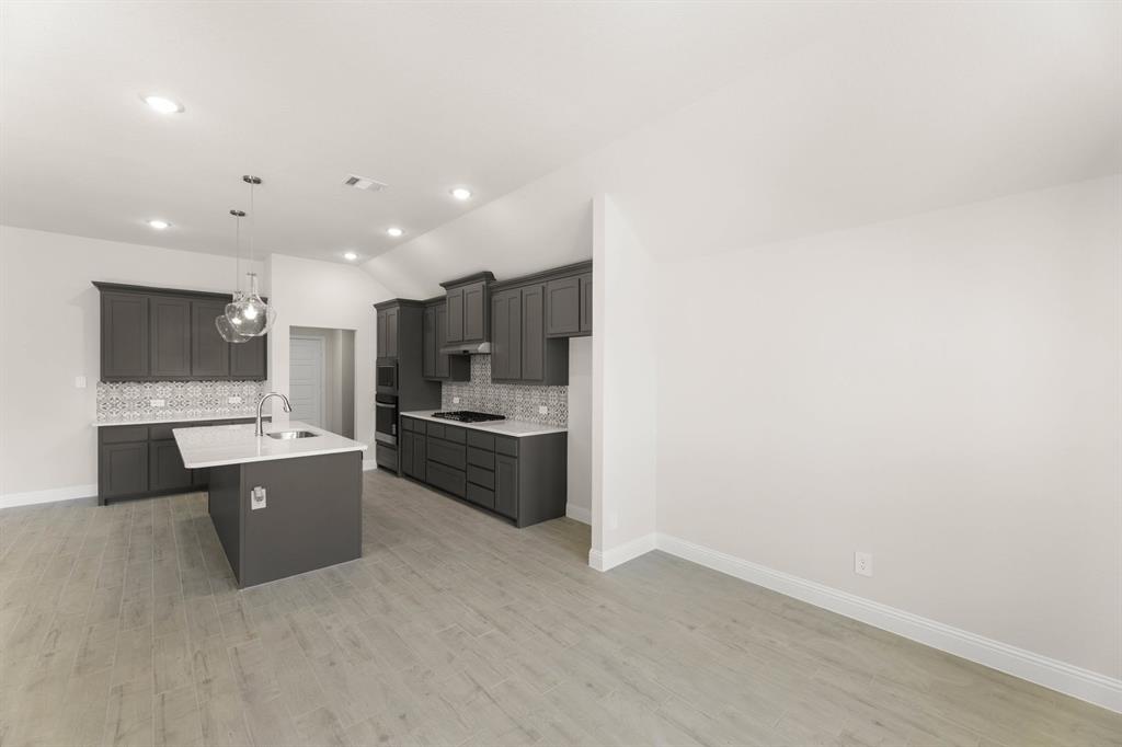 1007 Sedona Trail Justin, TX 76247 - Photo 7 of 40 a large room with kitchen island a sink a stove and a refrigerator with wooden floor