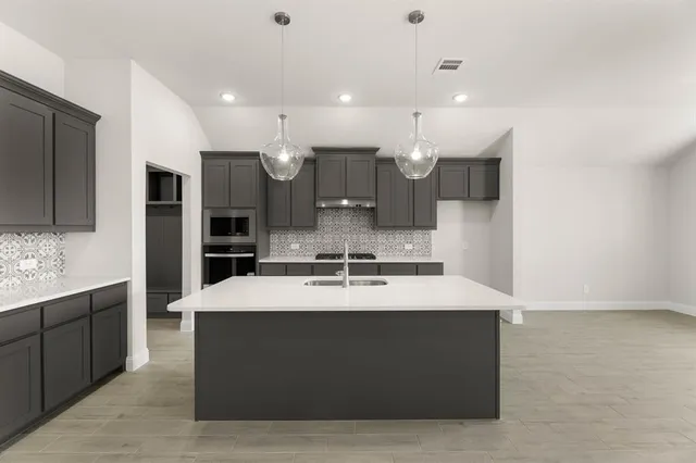 a large room with kitchen island a sink a stove and a refrigerator with wooden floor