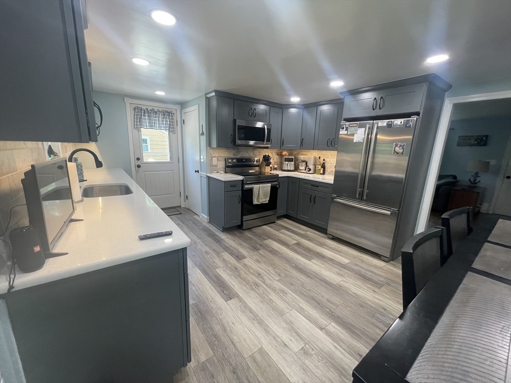 109 Oak Street Raynham, MA 02767 - Photo 3 of 9 a large kitchen with stainless steel appliances kitchen island granite countertop a sink refrigerator and cabinets