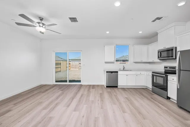 a kitchen with a refrigerator a stove top oven a sink and dishwasher with wooden floor