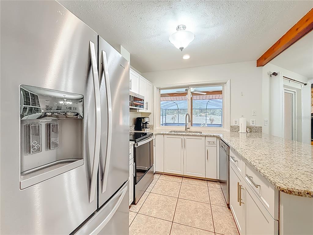 4353 North Indianhead Road Hernando, FL 34442 - Photo 19 of 65 a large white kitchen with granite countertop a refrigerator and a sink