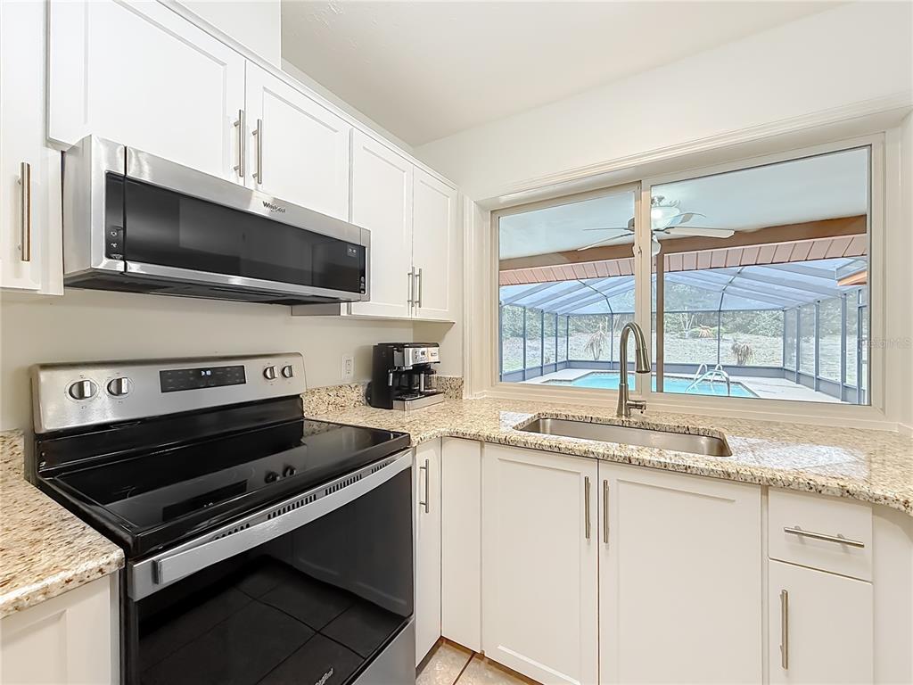4353 North Indianhead Road Hernando, FL 34442 - Photo 20 of 65 a kitchen with granite countertop a stove and a microwave