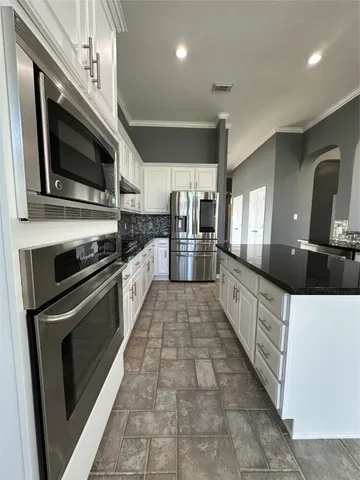 a kitchen with stainless steel appliances granite countertop a refrigerator and a stove