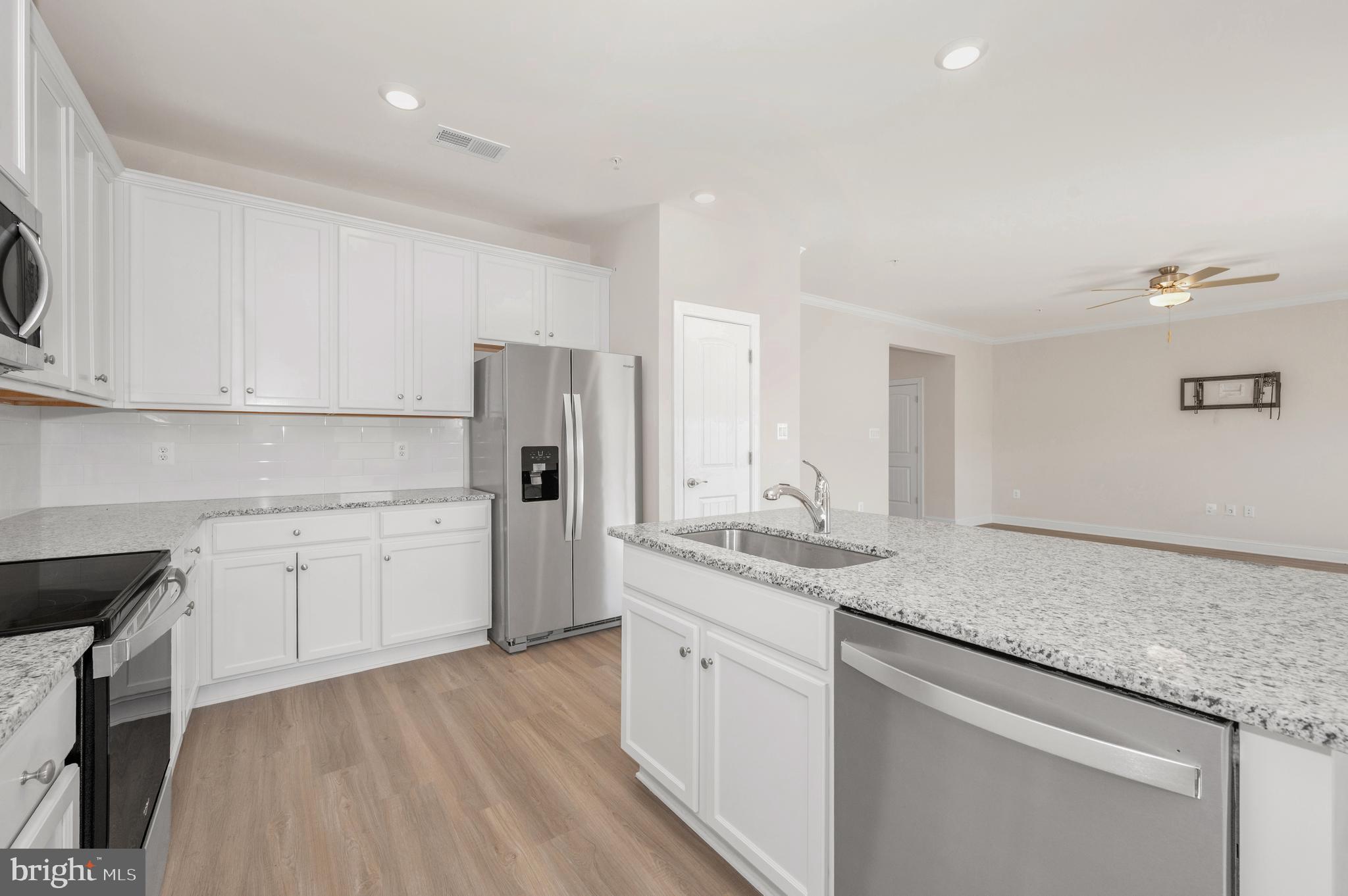 9962 Roulette Drive Hagerstown, MD 21740 - Photo 16 of 43 a kitchen with a sink dishwasher a refrigerator and white cabinets with wooden floor