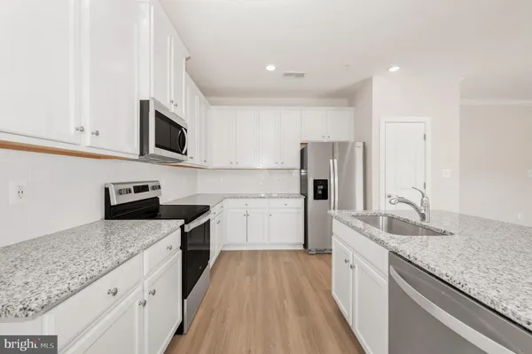 a kitchen with granite countertop a sink stainless steel appliances and white cabinets