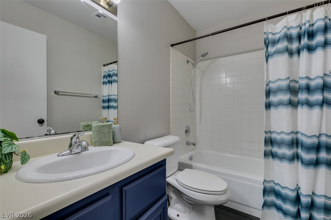 810 North Sloan Lane, Unit 103 Las Vegas, NV 89110 - Photo 7 of 16 Full bathroom featuring shower / tub combo with curtain, vanity, toilet, and a textured wall