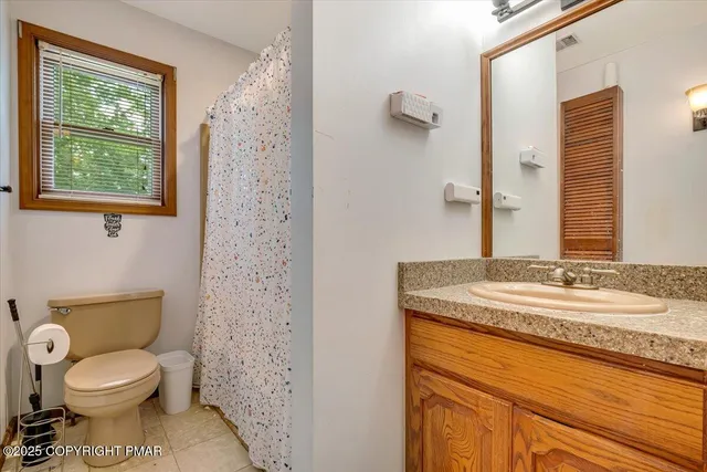 a bathroom with a granite countertop toilet a sink a mirror and a shower