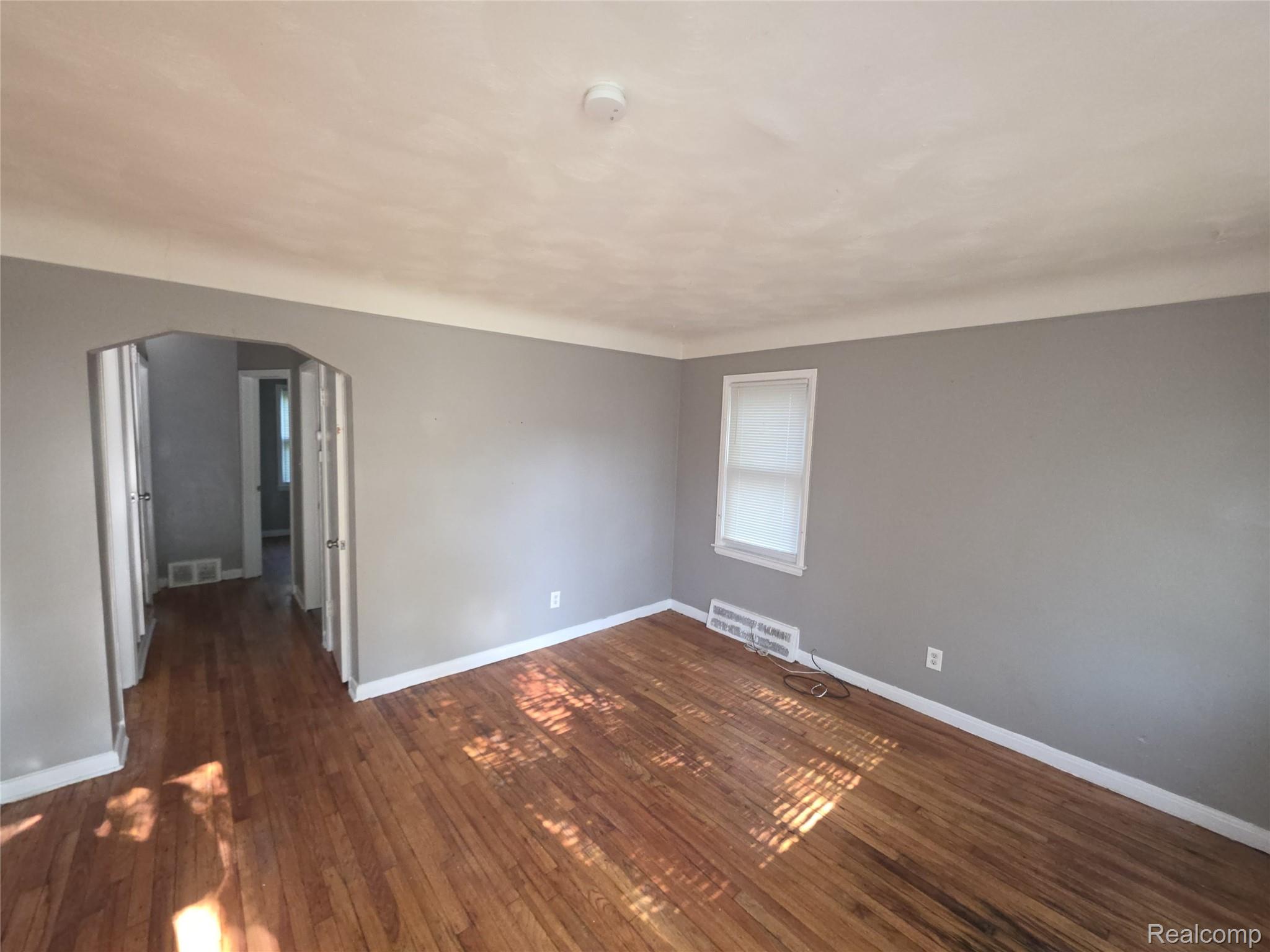 9025 Burt Road Detroit, MI 48228 - Photo 2 of 12 Spacious room featuring wood-finish flooring, light grey painted walls, white baseboards, and a single window with blinds