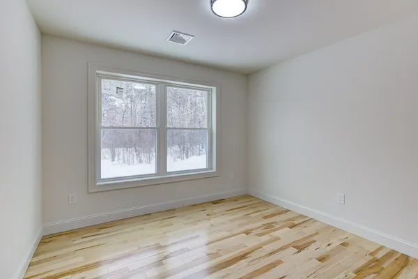 an empty room with wooden floor and windows