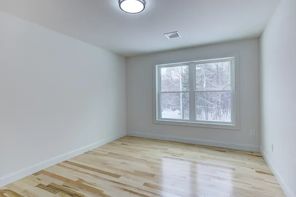 an empty room with wooden floor and windows
