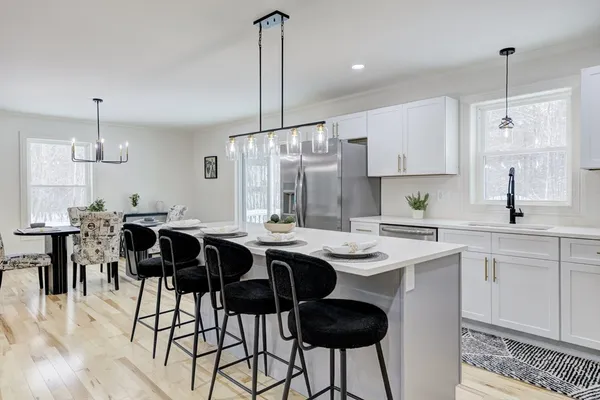 a kitchen with stainless steel appliances kitchen island granite countertop a sink a stove a refrigerator and island with wooden floor