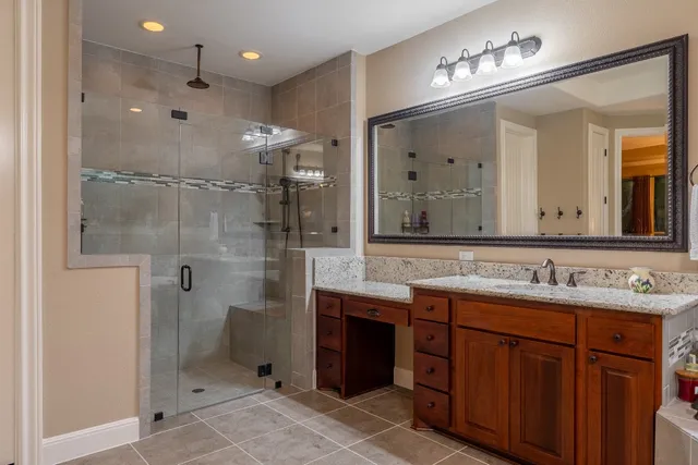 a bathroom with a double vanity sink mirror and shower