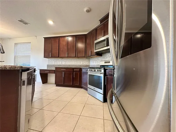 a kitchen with stainless steel appliances granite countertop a stove a sink and a refrigerator