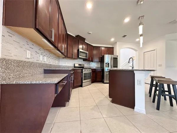 a kitchen with kitchen island granite countertop a sink a counter top space appliances and cabinets