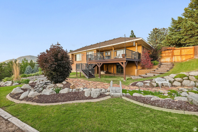 2342 Charros Road Sandy, UT 84092 - Photo 85 of 94 Terraced backyard featuring a multi-level deck, stone pathways, mature trees, and landscaping with decorative boulders