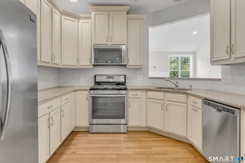 a kitchen with granite countertop white cabinets stainless steel appliances and sink